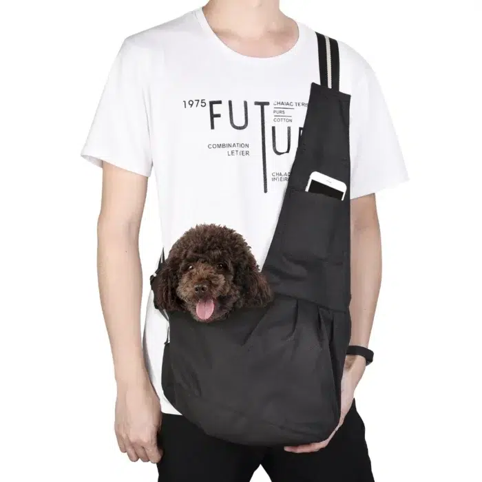 Homme sur fond blanc avec tee-shirt blanc avec écritures noires et jean noir portant un sac à bandoulière avec un chien marron à l'intérieur
