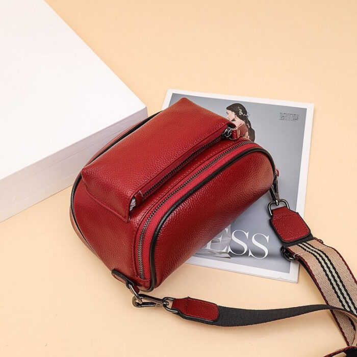 Sac à bandoulière rouge posé au sol avec un magazine derrière