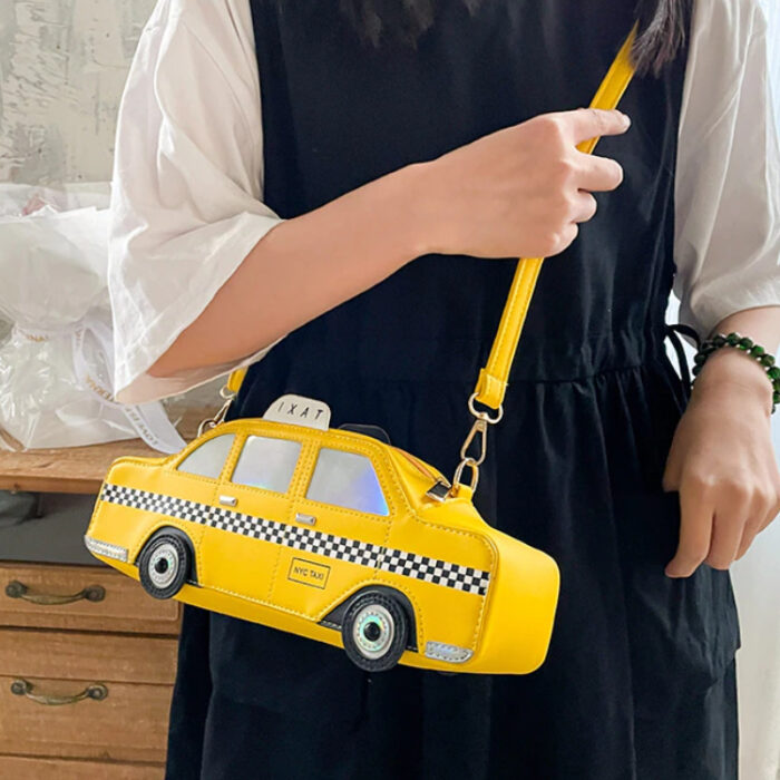 Femme en robe noire avec des manches blanches portant un sac jaune en bandoulière en forme de taxi