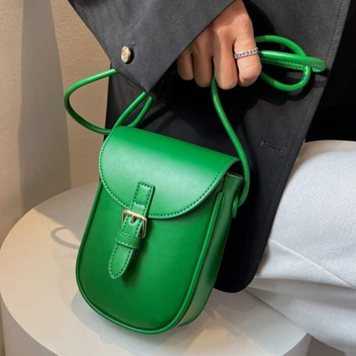Petit sac à bandoulière vert spécial forme de portable avec une sangle à l'avant en guise de fermeture.