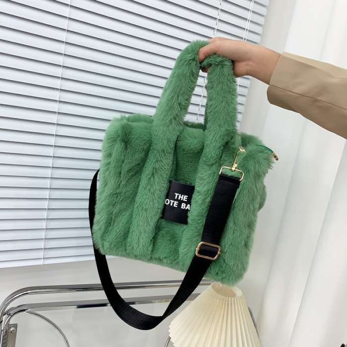 Photo d'un sac à main à bandoulière en fausse fourrure vert tenue par une main devant un volet.