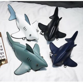 On voit quatre sacs à bandoulière qui représentent des requins : un vert, un noir, un blanc et un bleu marine. Ils sont en cuir synthétique et semblent plus vrais que nature.