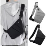 sac à dos bandoulière noir ou gris porté dans le dos par un homme avec un sweat à capuche