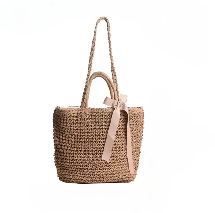 sac bandoulière en paille avec un noeud en satin sur fond blanc