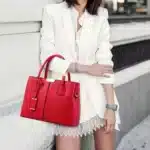 femme en tailleur blanc portant un sac à main bandoulière en cuir rouge dans la rue